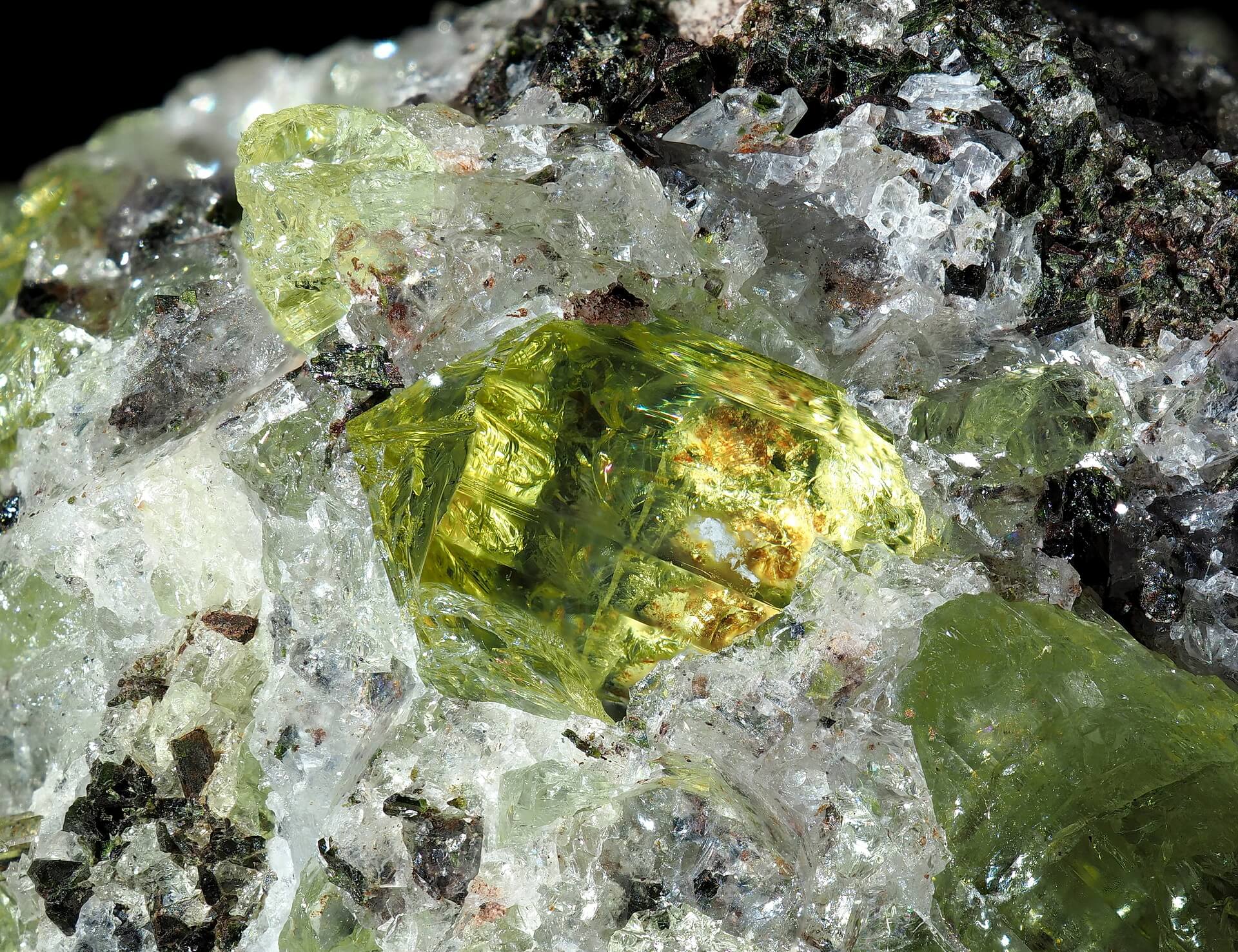 A very clear yellow Apatite crystal surrounded by white Calcite and dark green Augite.
